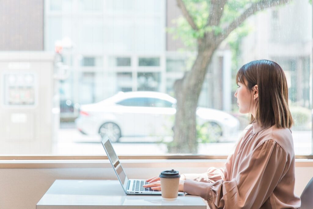 カフェでパソコンを使いながら考える女性